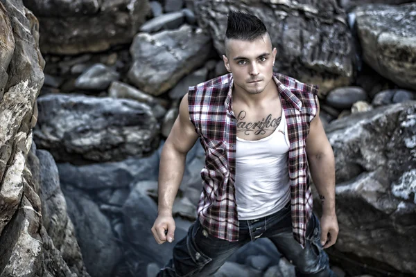 Handsome, muscular young man against rocks — Stock Photo, Image