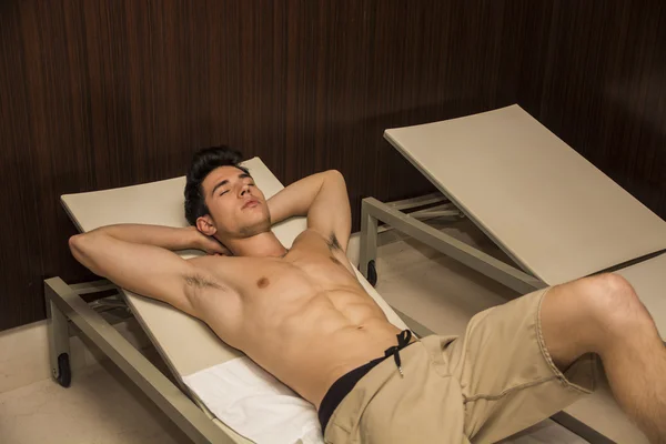 Jovem sem camisa relaxante na cadeira do salão Indoor — Fotografia de Stock