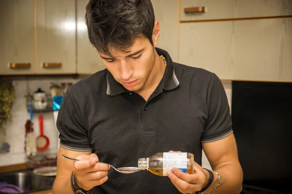 Sick young man taking cough syrup or medication — Stock Photo, Image