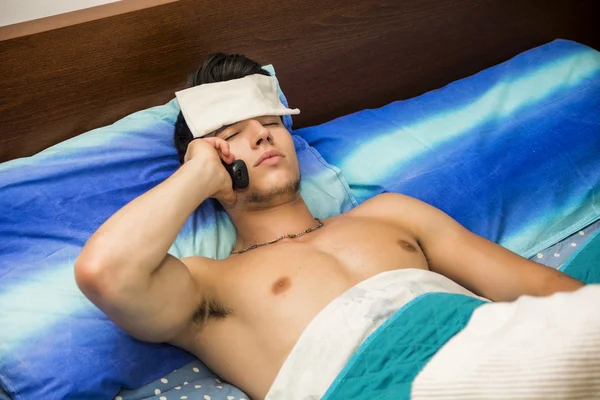 Mladý muž nemocný nebo nevolnosti v posteli volající lékaře — Stock fotografie