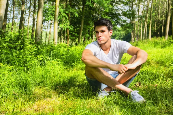 Přizpůsobit pohledný mladý muž relaxační, ležící na trávníku travní — Stock fotografie