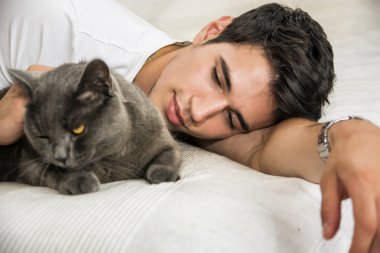 Handsome Young Man Cuddling his Gray Cat Pet clipart