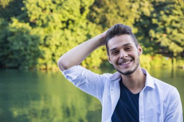 Nehir kenarında oturan düşünceli genç adam