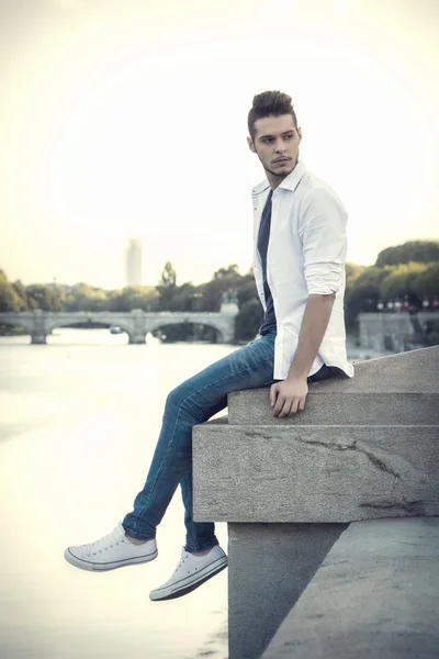 Contemplative young man sitting beside river — Stock Photo, Image