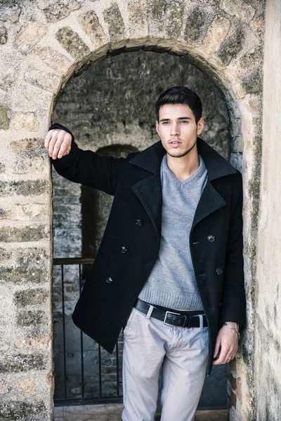 Attractive young man standing against brick wall — Stock Photo, Image