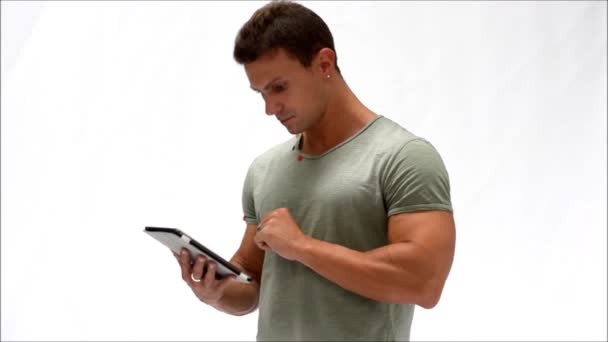 Мускулистый молодой человек, стоящий во время чтения с устройства электронной книги или с помощью планшетного ПК — стоковое видео