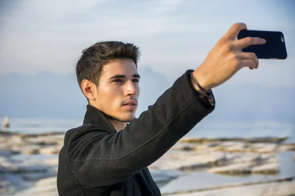 Knappe jonge man op een meer in een zonnige, rustige dag — Stockfoto