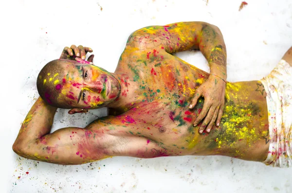 Aantrekkelijke jonge man shirtless tot op de vloer, huid geschilderd helemaal met kleuren — Stockfoto