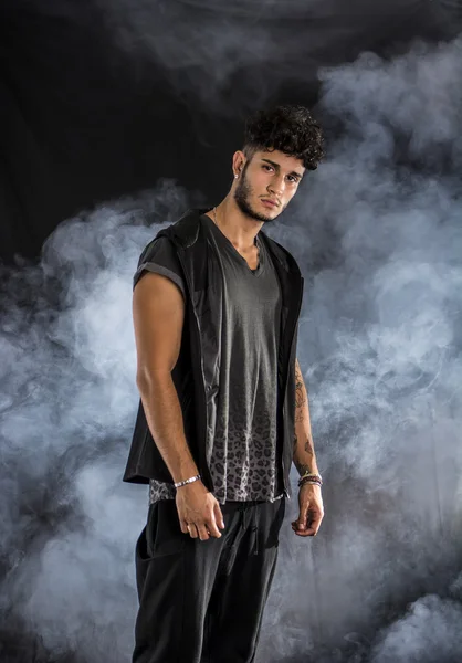 Tough young man in dark t-shirt on grey background — Stock Photo, Image