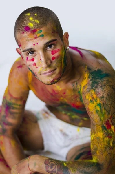 Knappe jongeman met huid allemaal geschilderd met Holi kleuren — Stockfoto
