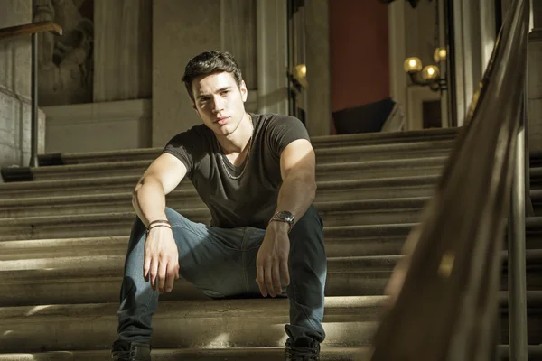 Young Man sitting on elegant stairs — Stock fotografie