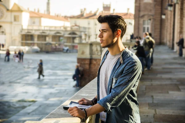 Joven sosteniendo una guía fuera del edificio histórico — Foto de Stock