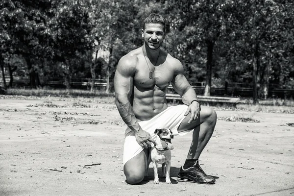 Sem camisa homem atlético com cachorro em seus braços — Fotografia de Stock