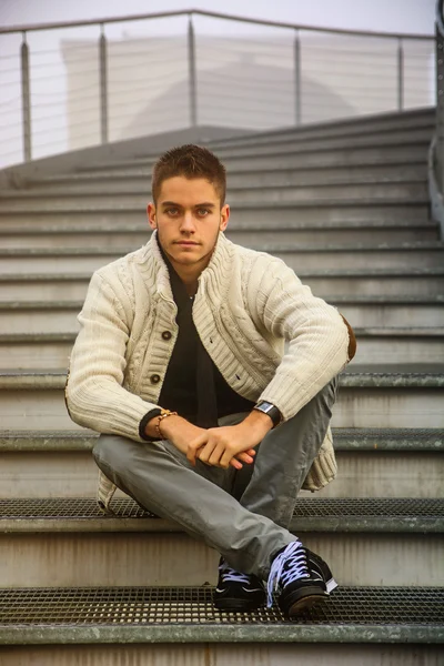 Rahat kıyafetler çapraz bacaklı oturan genç adam — Stok fotoğraf