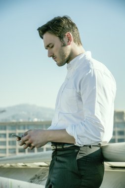 Metin yazmak için cep telefonu kullanan yakışıklı modacı.