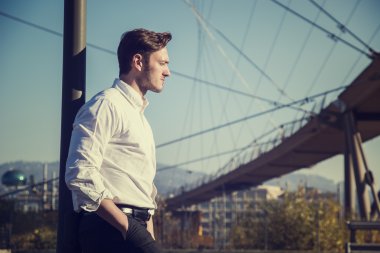 Dışarıda beyaz gömlekli yakışıklı bir genç var.