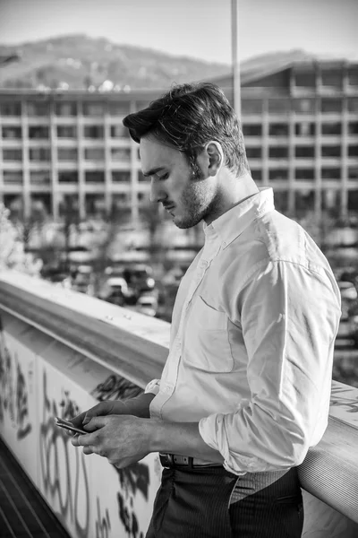 Handsome trendy man using cell phone to type text, outdoor — Stock Photo, Image