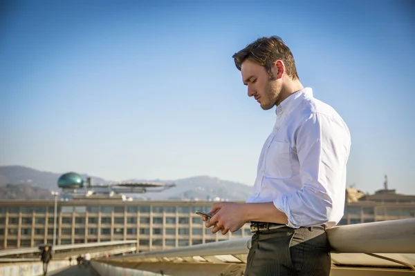 Schöner trendiger Mann mit Handy, um Text zu tippen, im Freien — Stockfoto
