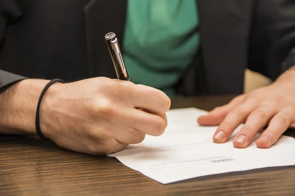 Ręce człowieka podpisanie arkusza papieru lub dokumentu — Zdjęcie stockowe