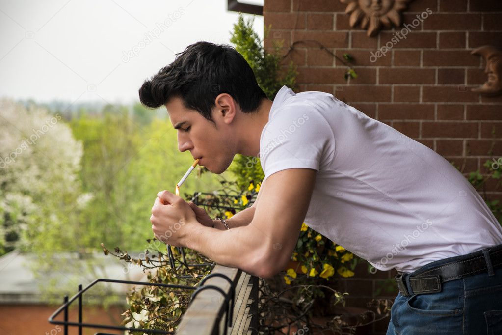 Handsome young man smoking a cigarette outside