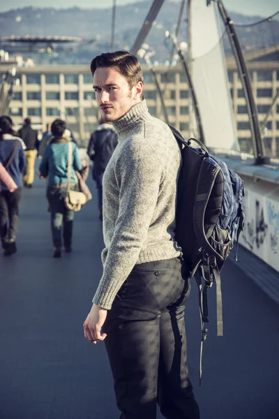 Handsome young man walking in city with backpack — Stock Photo, Image