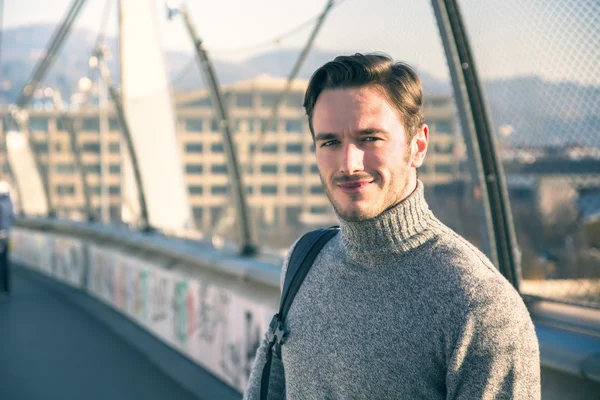 Handsome young man walking in city with backpack — Stock Photo, Image