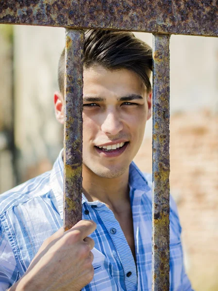 Pohledný mladý muž za mříže kovové klece — Stock fotografie