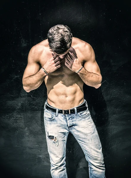 Handsome bearded shirtless young man standing against black wall — Stock Photo, Image