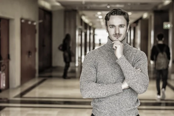 Jonge man in trui staande in de schoolhal — Stockfoto