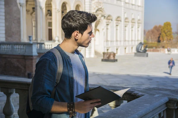 Young Man Holding a Guide outside Historic Building – stockfoto