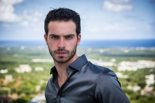 Portrait of man with curly hair standing against of shoreline — Stock Photo, Image