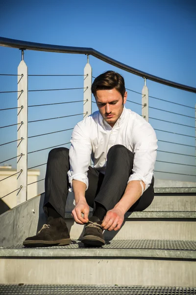Knappe man van de trendy sittiing op trappen, buiten — Stockfoto