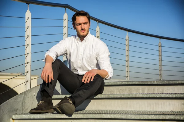 Knappe man van de trendy sittiing op trappen, buiten — Stockfoto