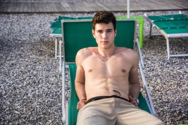 plajda şezlong güneşlenme gömleksiz genç adam