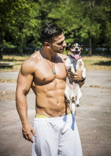 Camisa hombre atlético con perro en sus brazos — Foto de Stock