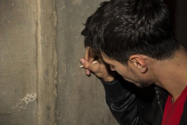 Close-up of young man writing on stone wall with pencil