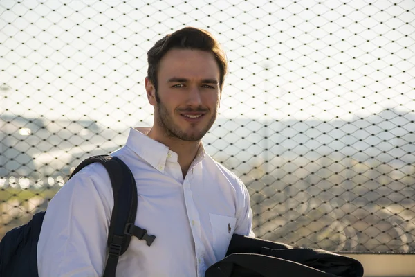 Handsome young man walking in city with backpack — Stock Photo, Image