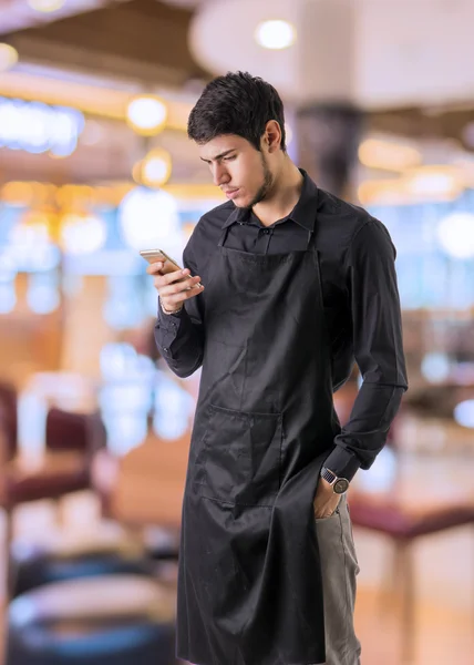 Jungen Koch oder Kellner tragen schwarze Schürze im restaurant — Stockfoto