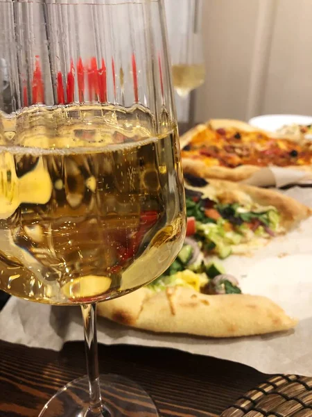 A glass of white wine and pizza