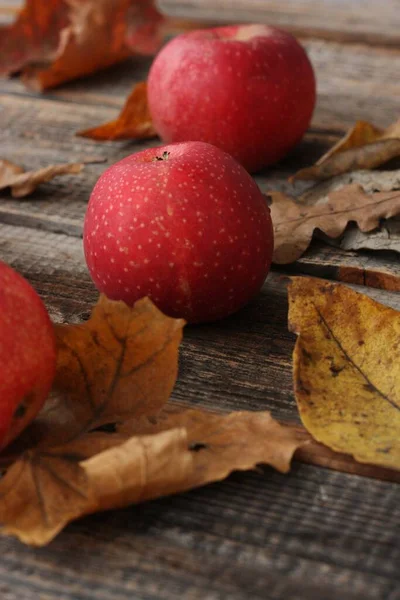 Saftige Rote Äpfel Und Herbstblätter Auf Dem Tisch — Stockfoto