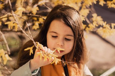 Kız çocuk ve ağaçların dallarında sıcacık çiçekler.