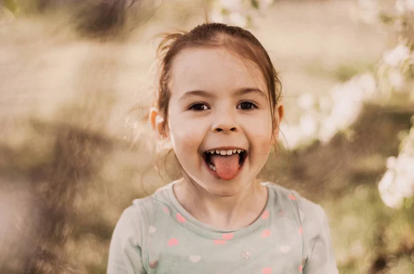 Dziewczyna Dziecko Pokazując Język Grimaces Zabawy Wiosnę Zewnątrz — Zdjęcie stockowe