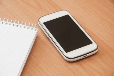 defter ve masanın üstünde hareket eden telefon