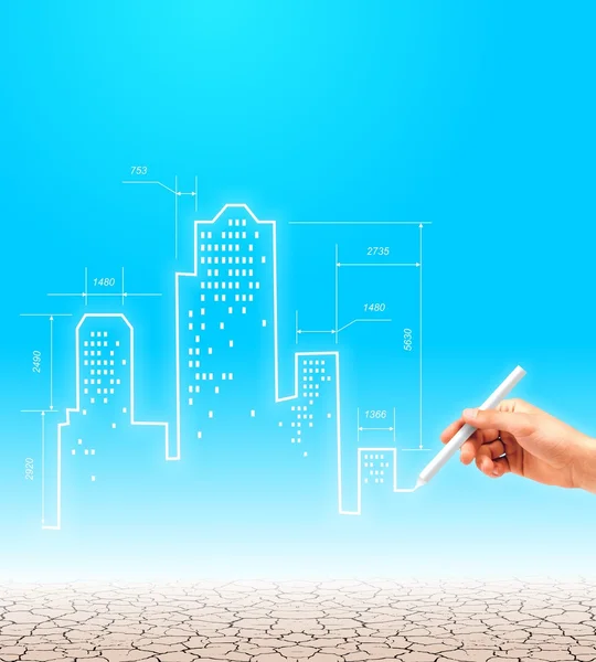 City of the future in the desert. Architectural project of construction of modern buildings in the desert. The engineer's hand draws a drawing of skyscrapers on the background of blue cloudless sky.