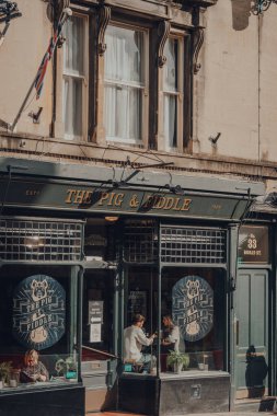 Bath, İngiltere - Ekim 04, 2020: Somerset 'in bilinen ve adını Roma hamamlarından alan en büyük şehri olan Bath' daki The Pig & Fiddle İngiliz barının dışında, insanlar pencere kenarında oturuyorlar..