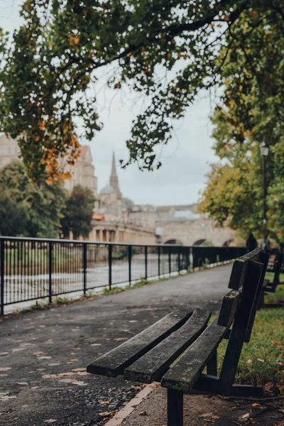 空荡荡的长椅在雅芳河岸上 背景在英国巴斯市 有选择地聚焦 — 图库照片