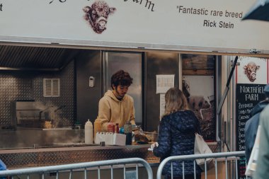 Londra, İngiltere - 19 Kasım 2020: Londra 'nın en büyük ve en eski gıda pazarlarından biri olan Borough Market' teki Northfield Farm gıda kamyonundan yemek sipariş eden kadın.
