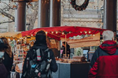 Londra, İngiltere - 19 Kasım 2020: İngiltere 'nin en büyük ve en eski gıda pazarlarından biri olan Borough Market' teki tezgahta koruyucu yüz maskesi takan satıcı. Seçici odak.