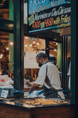 Londra, İngiltere - 19 Kasım 2020: Koruyucu yüz maskesi takan çalışanlar, Londra, İngiltere 'deki en büyük ve en eski gıda pazarlarından biri olan Borough Market' teki gıda standında çalışıyor..