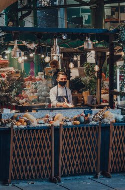 Londra, İngiltere - 19 Kasım 2020: Londra, İngiltere 'deki en büyük ve en eski gıda pazarlarından biri olan Borough Market' teki gıda standında koruyucu yüz maskesi takan çalışanlar.